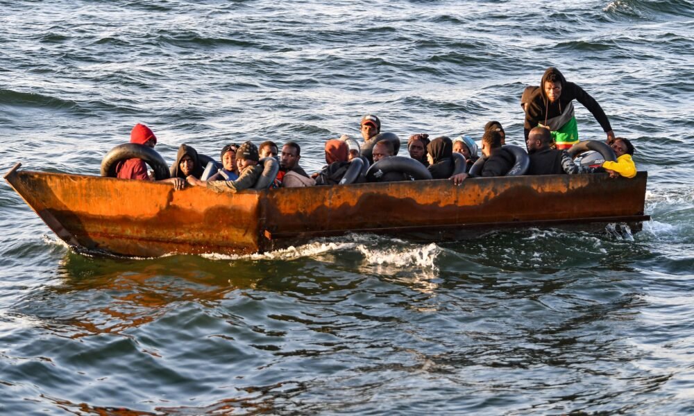Refugiados de África subsahariana se sientan en una lancha improvisada interceptada por las autoridades tunisinas a unos 50 millas náuticas en el mar Mediterráneo frente a la costa de la ciudad de Sfax [Foto: Fethi Belaid/AFP]