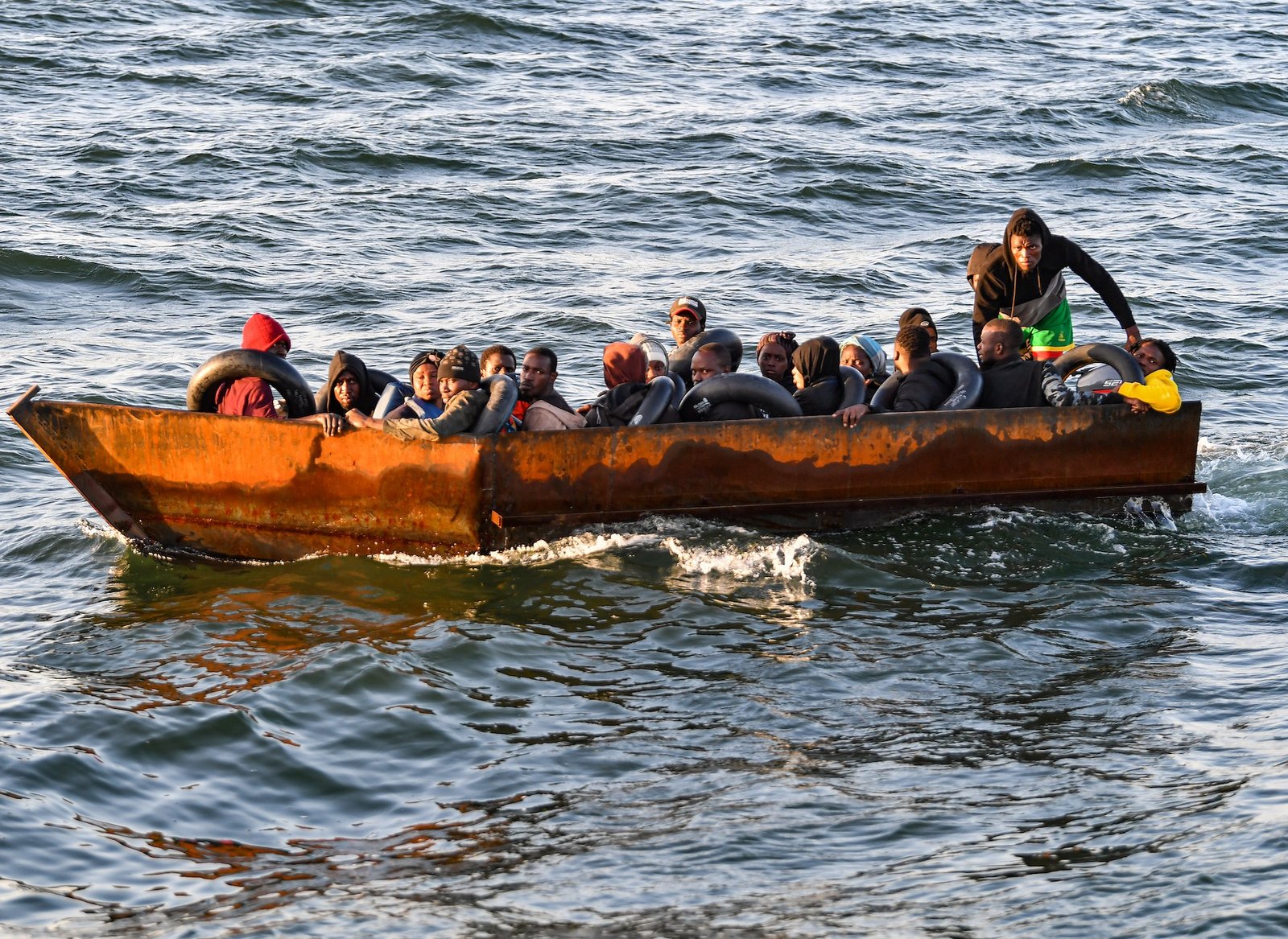 Refugiados de África subsahariana se sientan en una lancha improvisada interceptada por las autoridades tunisinas a unos 50 millas náuticas en el mar Mediterráneo frente a la costa de la ciudad de Sfax [Foto: Fethi Belaid/AFP]