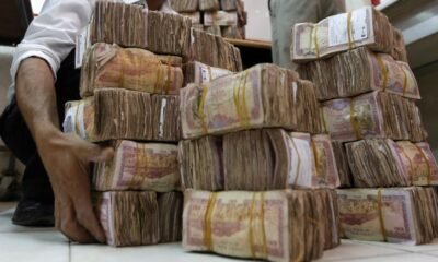 Trabajador transporta pilas de moneda yemení en el Banco Central de Yemen en Sanaa [Archivo: Khaled Abdullah/Reuters]