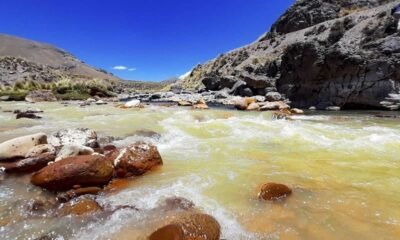 Alcaldes afectados contaminación — Un río de aguas turbias fluye sobre rocas en un paisaje montañoso bajo un cielo azul despejado. Foto de: El Búho