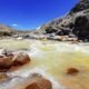 Alcaldes afectados contaminación — Un río de aguas turbias fluye sobre rocas en un paisaje montañoso bajo un cielo azul despejado. Foto de: El Búho