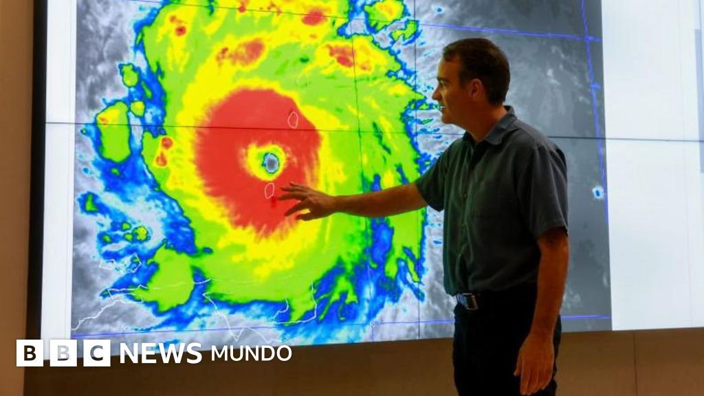 Especialistas monitorean — Un funcionario de meteorología de EE.UU. señala un gráfico de un huracán. Tomada por: BBC Mundo