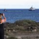 Finaliza evacuación Hondius — Una mujer fotografía la salida del crucero 'Hondius' en el puerto de Granadilla de Abona, en Tenerife, España, el 11 de mayo. Hannah McKay (REUTERS)