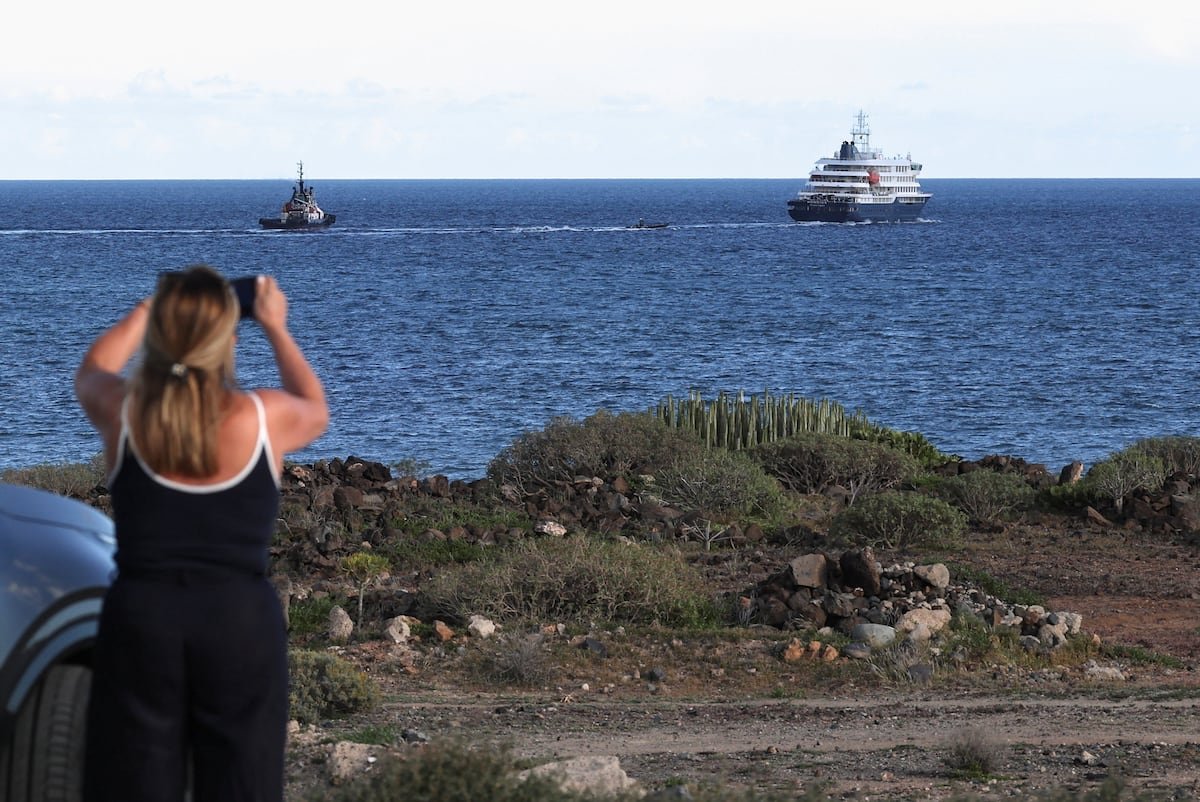 Finaliza evacuación Hondius — Una mujer fotografía la salida del crucero 'Hondius' en el puerto de Granadilla de Abona, en Tenerife, España, el 11 de mayo. Hannah McKay (REUTERS)