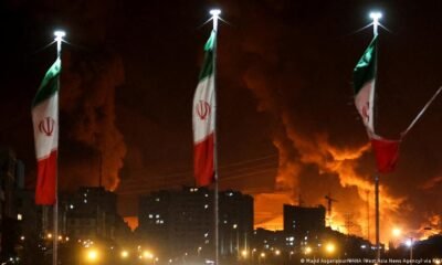 Hezbolá ataca Israel — Banderas de Irán con columnas de humo detrás.. Foto de: © Majid Asgaripour/WANA (West Asia News Agency) via REUTERS