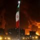 Hezbolá ataca Israel — Banderas de Irán con columnas de humo detrás.. Foto de: © Majid Asgaripour/WANA (West Asia News Agency) via REUTERS