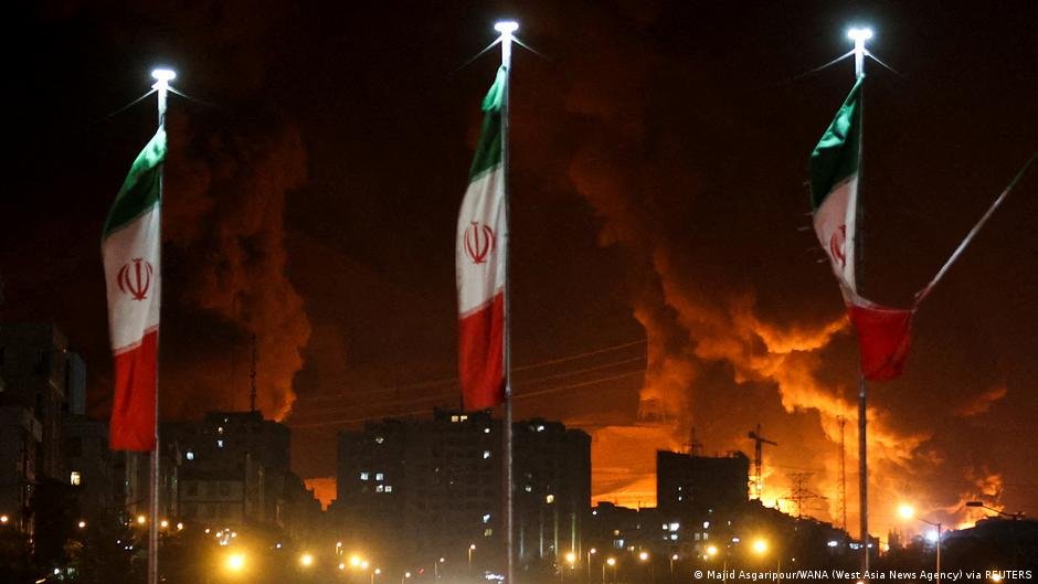 Hezbolá ataca Israel — Banderas de Irán con columnas de humo detrás.. Foto de: © Majid Asgaripour/WANA (West Asia News Agency) via REUTERS