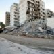 Israel bombardea suburbio — Una mujer toma una foto junto a edificios dañados en el sitio de un bombardeo aéreo israelí que afectó una sucursal en los suburbios sureños de Beirut [Foto: Ibrahim Amro/AFP]