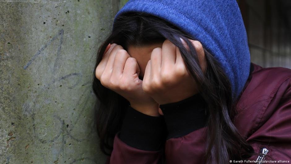 abuso sexual conflicto — Una foto de archivo muestra a una niña con capucha y manos cubriendo su cara. Tomada por: DW English