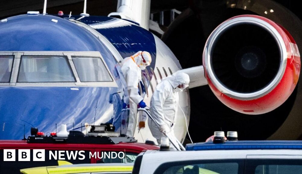 OMS advierte rastreo — Personas con ropa de protección personal descienden de un avión.