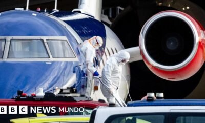 OMS advierte rastreo — Personas con ropa de protección personal descienden de un avión.