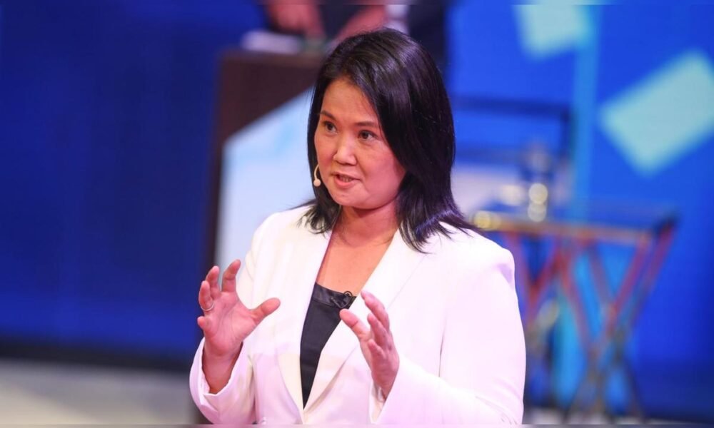Poder Judicial — Una mujer con blazer blanco y cabello oscuro gesticula mientras habla en un evento con fondo azul. Foto de: La República