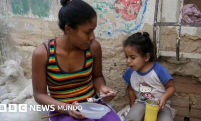 producción mundial — Una mujer alimenta a una niña en el barrio La Bombilla en Caracas.