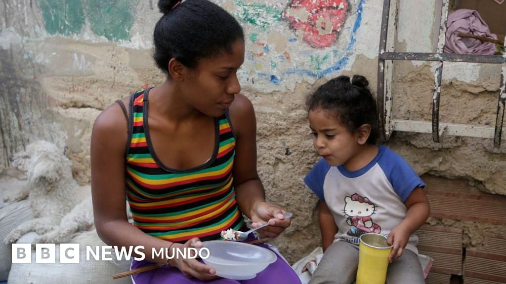 producción mundial — Una mujer alimenta a una niña en el barrio La Bombilla en Caracas.
