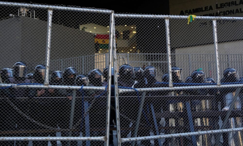 presidente Paz — La policía mantiene la guardia detrás de una valla durante las protestas anti-gobierno cerca del palacio en La Paz, Bolivia. Foto de: Juan Karita/AP Photo