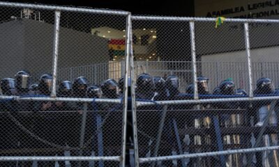 presidente Paz — La policía mantiene la guardia detrás de una valla durante las protestas anti-gobierno cerca del palacio en La Paz, Bolivia. Foto de: Juan Karita/AP Photo