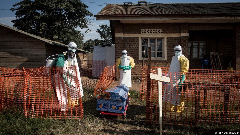 brote ébola — Funcionarios en equipo de protección personal desinfectan un ataúd en un centro de tratamiento para pacientes con ébola en la RDC. Foto de: Imagen: John Wessels/AFP