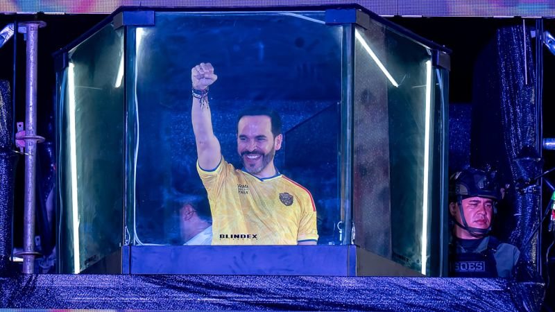 estrecha ventaja — El futbolista Sergio Agüero celebra con el puño en alto mientras aparece dentro de una estructura transparente iluminada. Foto de: news.google.com