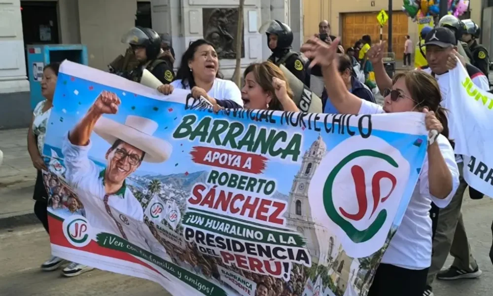 protestas voto popular — Varias personas sostienen una gran pancarta con el rostro de un hombre con sombrero y el nombre de Roberto Sánchez. Foto de: news.google.com