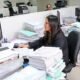 gratificaciones y CTS trabajadores — Mujeres trabajan en oficinas con grandes pilas de papeles y carpetas sobre los escritorios frente a monitores. Foto de: Gestión