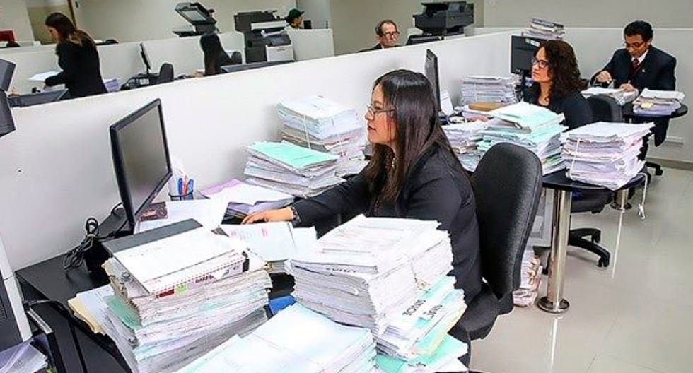 gratificaciones y CTS trabajadores — Mujeres trabajan en oficinas con grandes pilas de papeles y carpetas sobre los escritorios frente a monitores. Foto de: Gestión