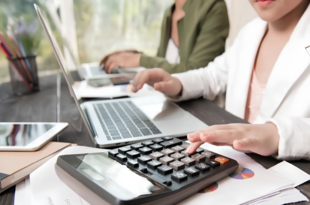 calculo pago feriado peruano — Una persona utiliza una calculadora y una computadora para realizar cálculos financieros sobre el pago de horas extra en días feriados. Foto de: Perú21