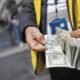Dólar estadounidense — Unas manos sostienen fajos de dólares estadounidenses en un entorno urbano, ilustrando la fluctuación del tipo de cambio. Foto de: Gestión