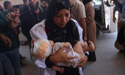 Fuerzas israelíes — Una enfermera palestina carga a un niño herido en el hospital Nasser tras los ataques israelíes contra campamentos de desplazados en la Franja de Gaza. Foto de: AFP