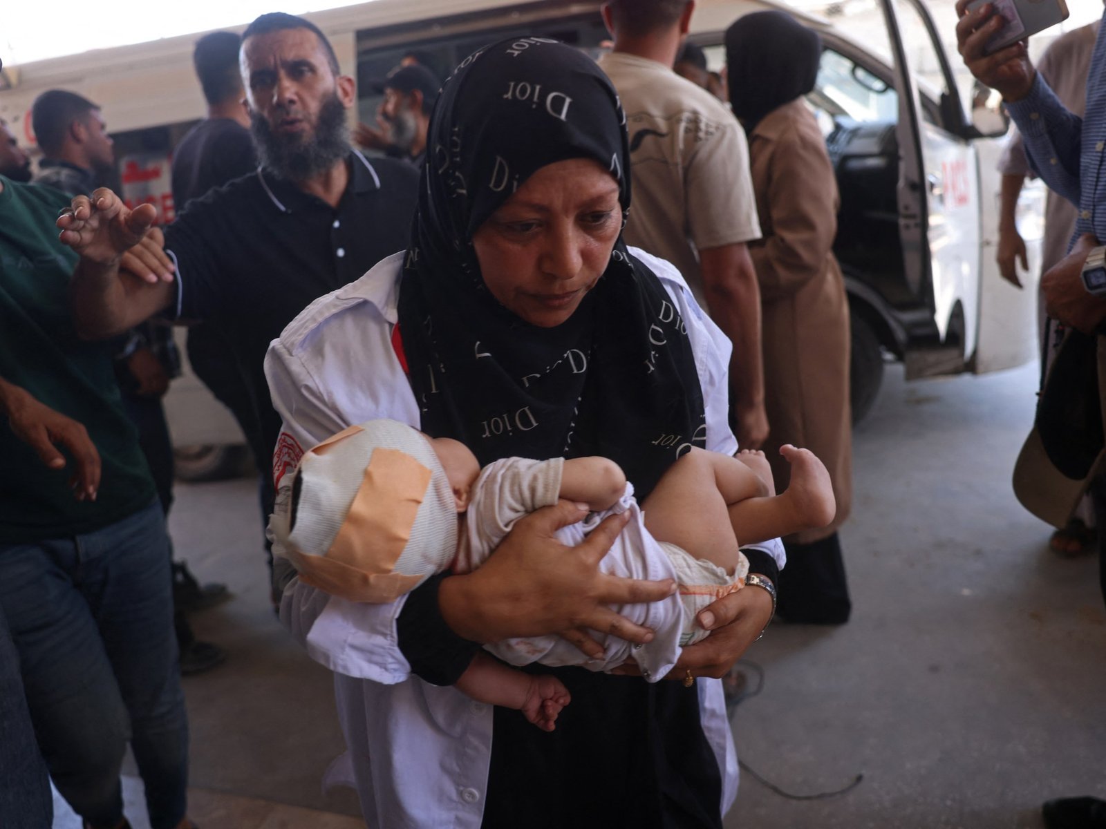 Fuerzas israelíes — Una enfermera palestina carga a un niño herido en el hospital Nasser tras los ataques israelíes contra campamentos de desplazados en la Franja de Gaza. Foto de: AFP