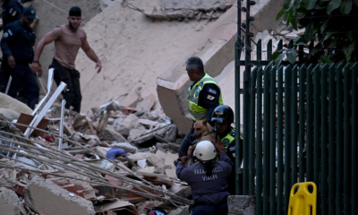 ayuda humanitaria — Personal de rescate y un perro de búsqueda trabajan entre los escombros tras un desastre en una zona urbana. Foto de: Perú21