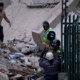ayuda humanitaria — Personal de rescate y un perro de búsqueda trabajan entre los escombros tras un desastre en una zona urbana. Foto de: Perú21