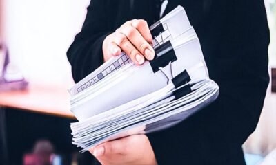 Una persona sostiene un expediente de documentos legales que representan la eliminación de barreras burocráticas por parte de Indecopi. Foto de: El Peruano