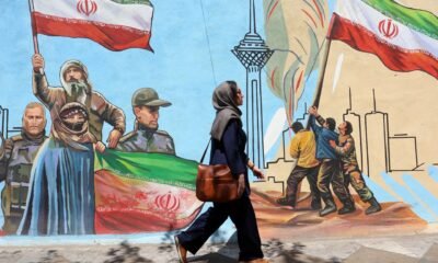 Irán avanza negociaciones — Una mujer iraní camina por una calle de Teherán pasando junto a un mural colorido pintado en la pared. Foto de: EPA