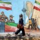 Irán avanza negociaciones — Una mujer iraní camina por una calle de Teherán pasando junto a un mural colorido pintado en la pared. Foto de: EPA