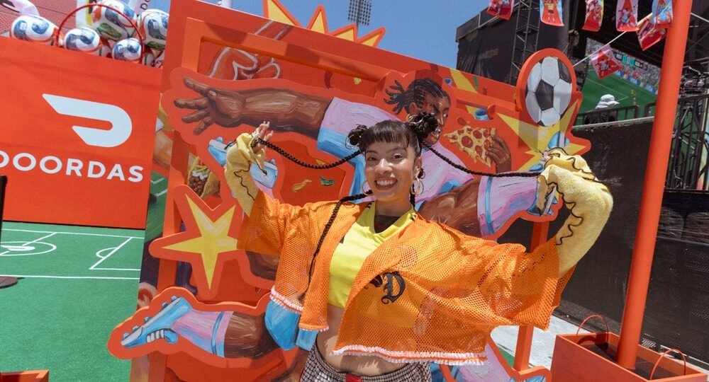 Janella Hernandez posa con una chaqueta de fútbol frente a un mural artístico en el festival de la FIFA en Los Ángeles. Foto de: Hypebeast