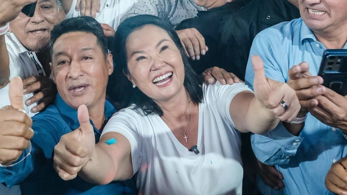 fraude electoral — Una mujer sonriente y un hombre a su lado muestran el pulgar hacia arriba frente a otras personas. Foto de: El Búho