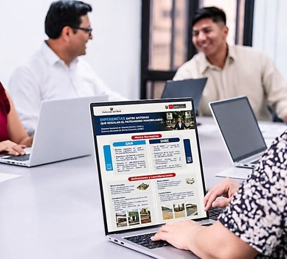 bienes inmuebles — Tres personas trabajan frente a computadoras portátiles en una mesa larga, analizando información en pantallas durante una reunión. Foto de: El Peruano