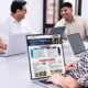bienes inmuebles — Tres personas trabajan frente a computadoras portátiles en una mesa larga, analizando información en pantallas durante una reunión. Foto de: El Peruano