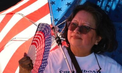 ola de calor — Una mujer sostiene un abanico con motivos de la bandera estadounidense mientras se prepara para las celebraciones del 4 de julio. Foto de: CNN en Español