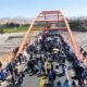 paro indefinido — Una multitud de personas camina y se agrupa sobre un puente de estructura naranja bajo un cielo despejado. Foto de: La República