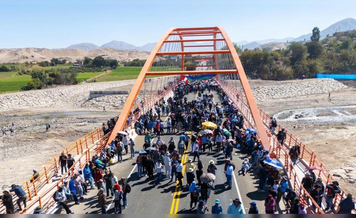 paro indefinido — Una multitud de personas camina y se agrupa sobre un puente de estructura naranja bajo un cielo despejado. Foto de: La República
