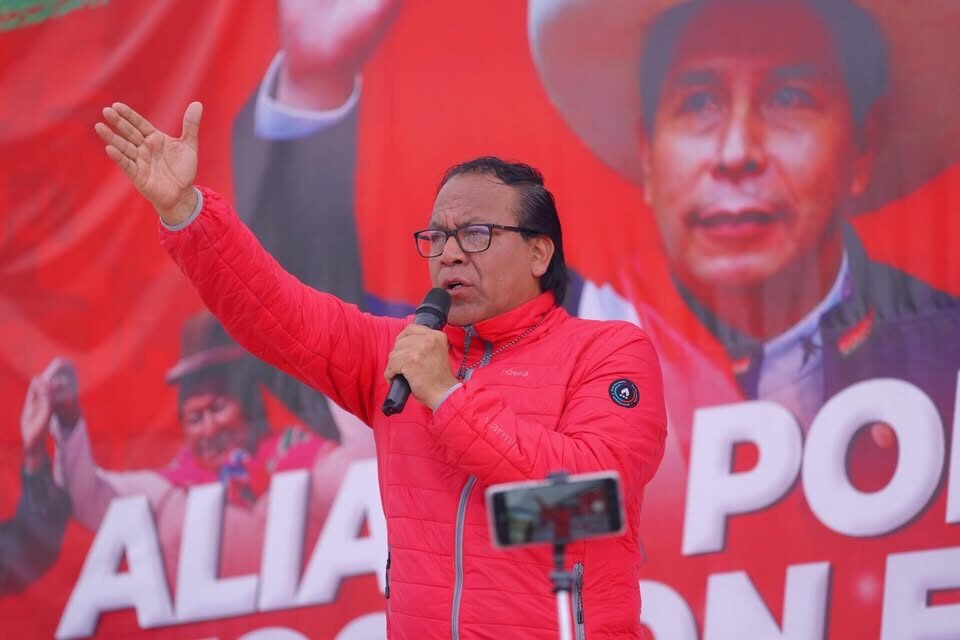 Roberto Sánchez — Un hombre con una chaqueta roja habla frente a un micrófono ante un cartel que menciona la palabra 'ALIANZA'. Foto de: news.google.com
