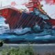 acuerdo Irán — Una persona camina frente a un mural que muestra un barco en llamas, simbolizando la inestabilidad y tensión en el conflicto de Medio Oriente. Foto de: news.google.com