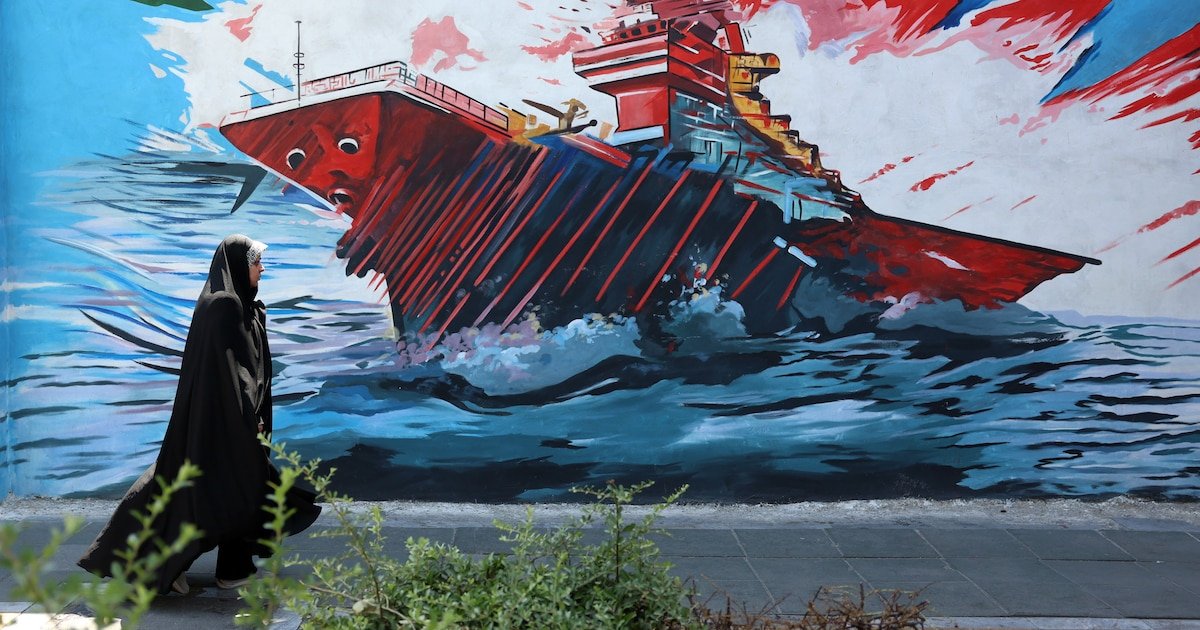 acuerdo Irán — Una persona camina frente a un mural que muestra un barco en llamas, simbolizando la inestabilidad y tensión en el conflicto de Medio Oriente. Foto de: news.google.com