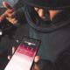 Amenazas través WhatsApp — Una persona sostiene un teléfono móvil mostrando una aplicación de mensajería mientras se encuentra cerca de una motocicleta. Foto de: Gestión
