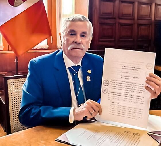Congreso promulga ley — Un funcionario muestra un documento oficial relacionado con la nueva ley que sanciona a policías y militares por colaborar con criminales. Foto de: El Peruano
