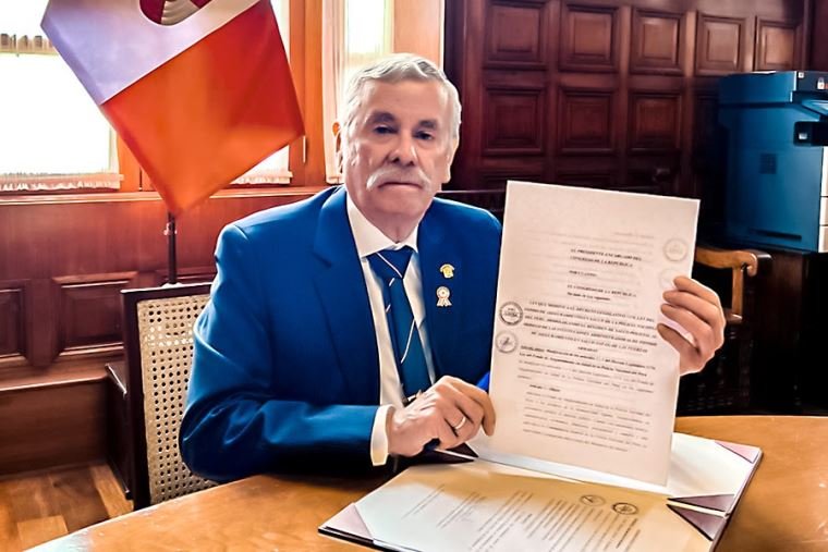 Congreso promulga ley — Un funcionario muestra un documento oficial relacionado con la nueva ley que sanciona a policías y militares por colaborar con criminales. Foto de: El Peruano