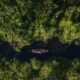 riesgo económico — Una vista aérea de una canoa navegando por un río rodeado de densa vegetación, ilustrando la problemática de la deforestación en Perú. Foto de: Gestión