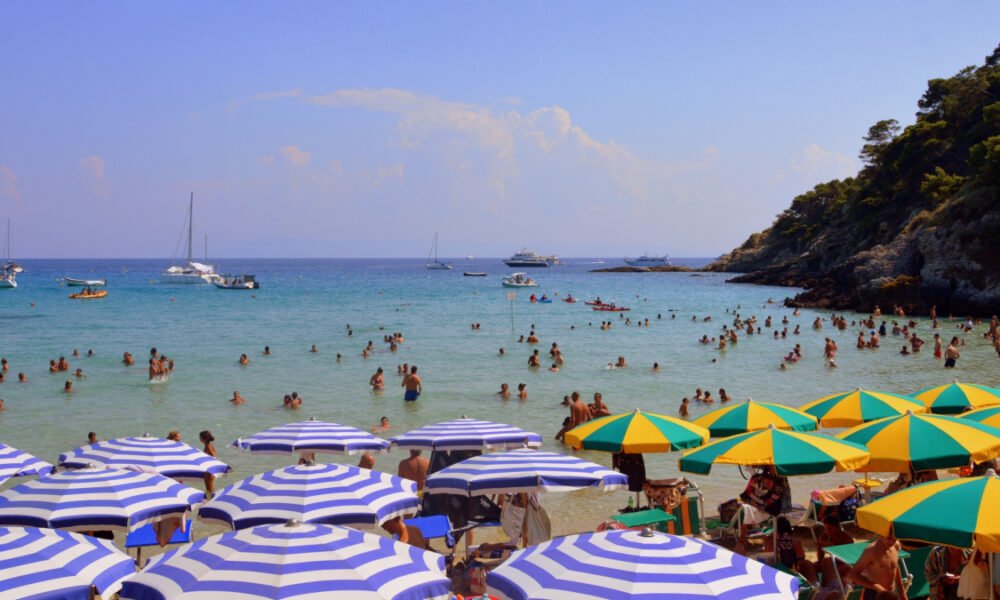 ola calor España — Bañistas disfrutan de las aguas del mar en una playa con sombrillas durante la ola de calor en España. Foto de: Pixabay