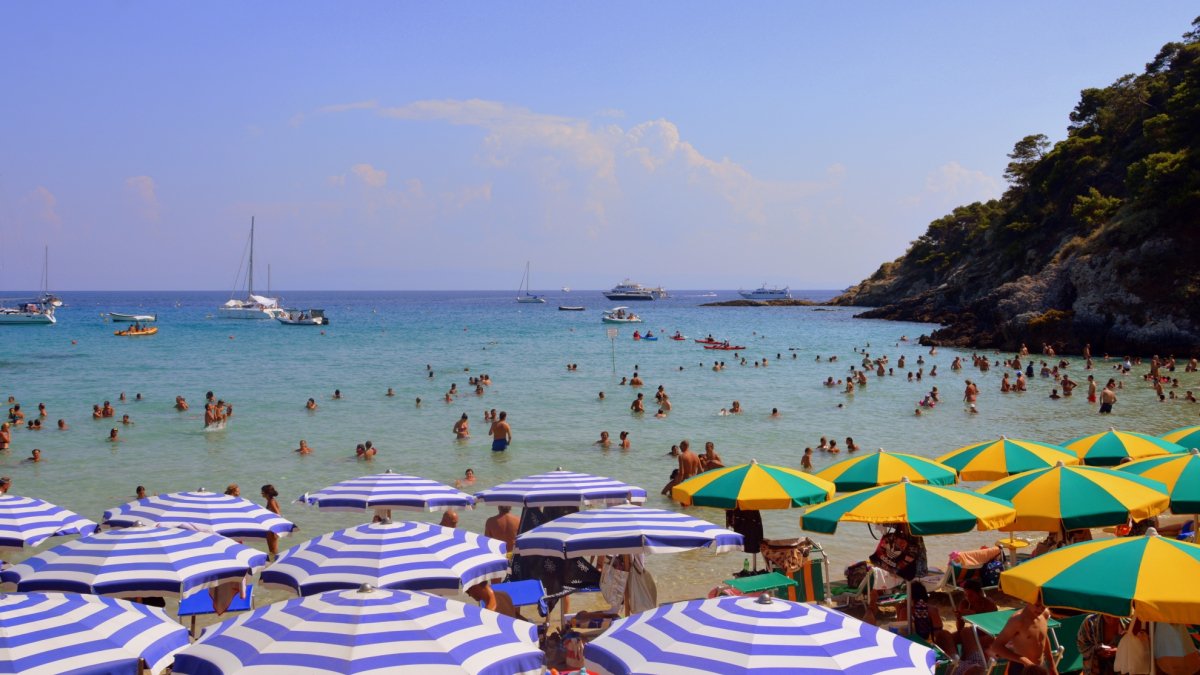 ola calor España — Bañistas disfrutan de las aguas del mar en una playa con sombrillas durante la ola de calor en España. Foto de: Pixabay